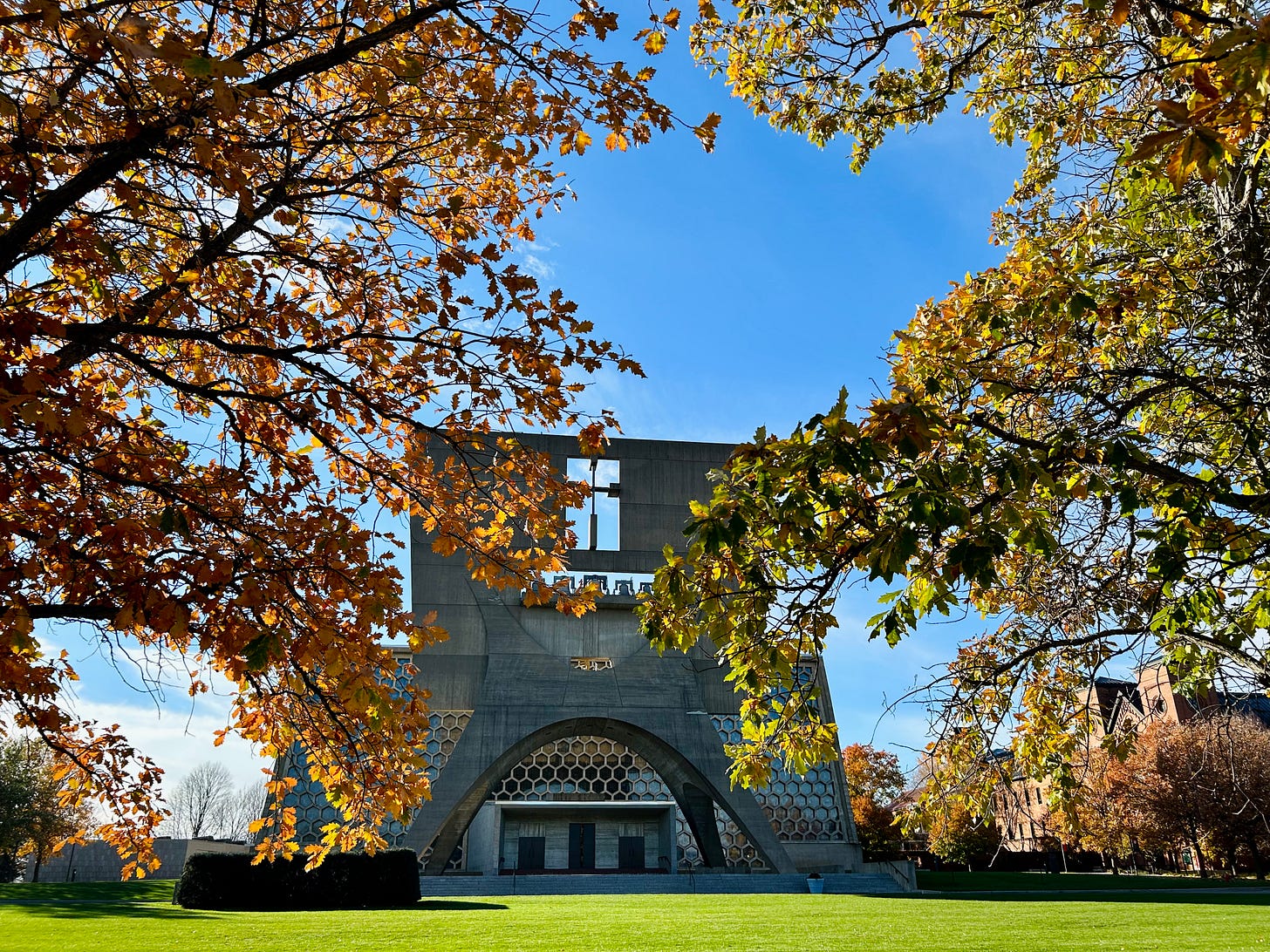 a concrete chapel behind fall trees