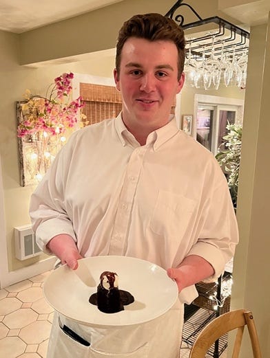 A person holding a plate of dessert

Description automatically generated