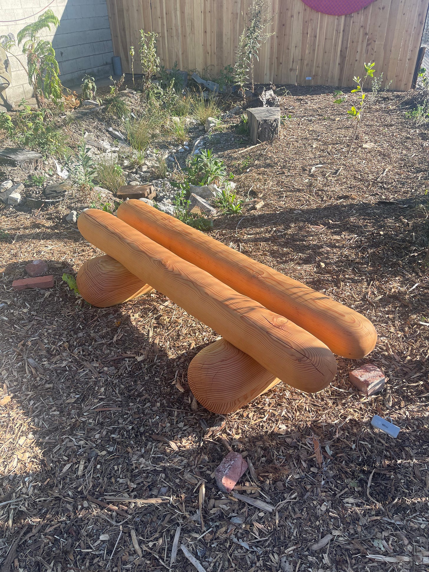 Ryan Belli's wooden bench that looks like two breadsticks in the setting of a garden