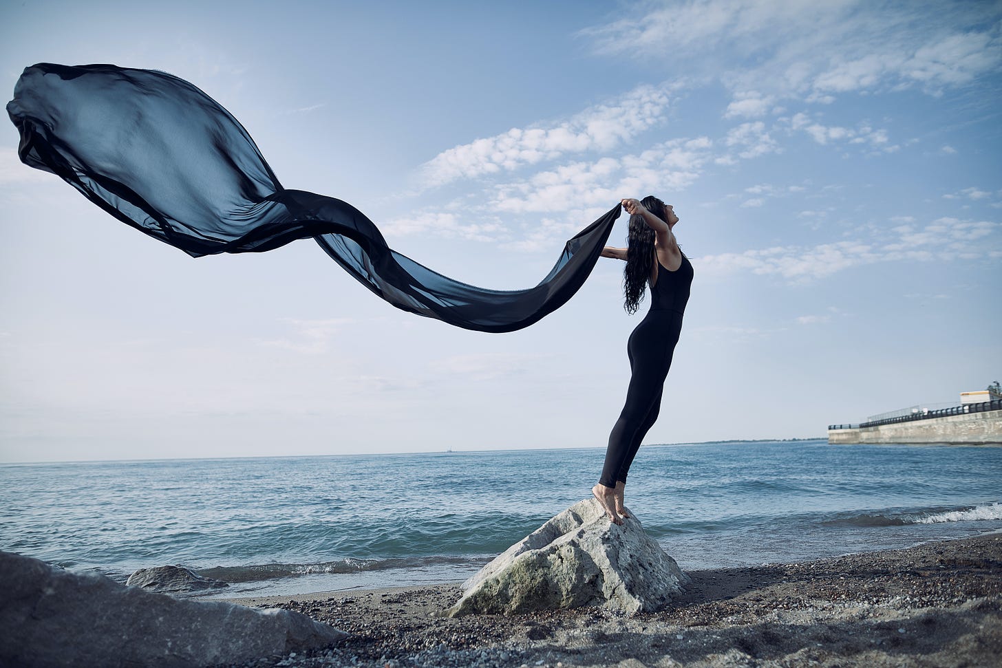 Woman with feet on a rock scarf flying behind her