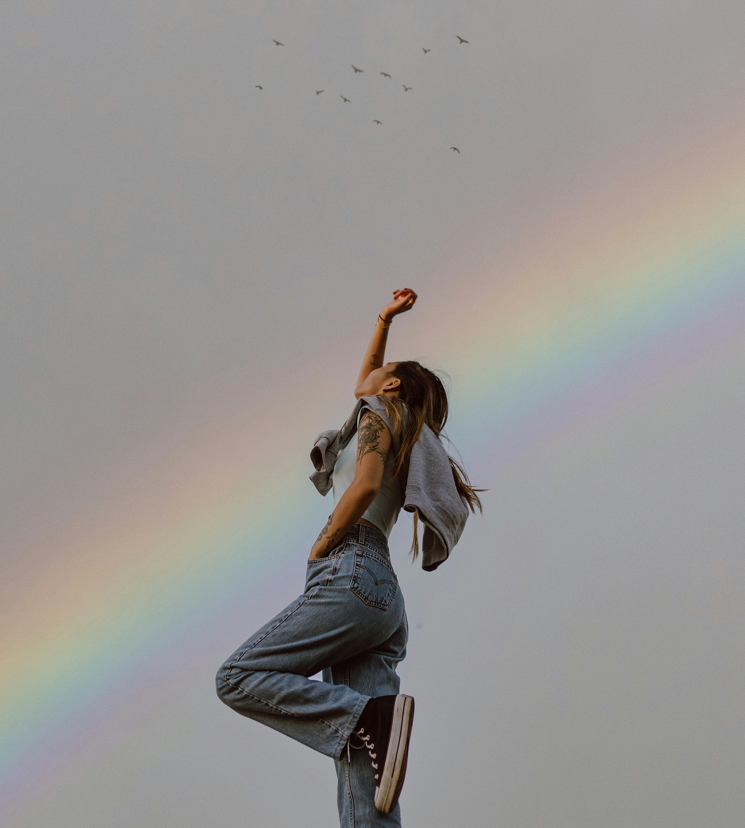 Woman raising arm and rainbow