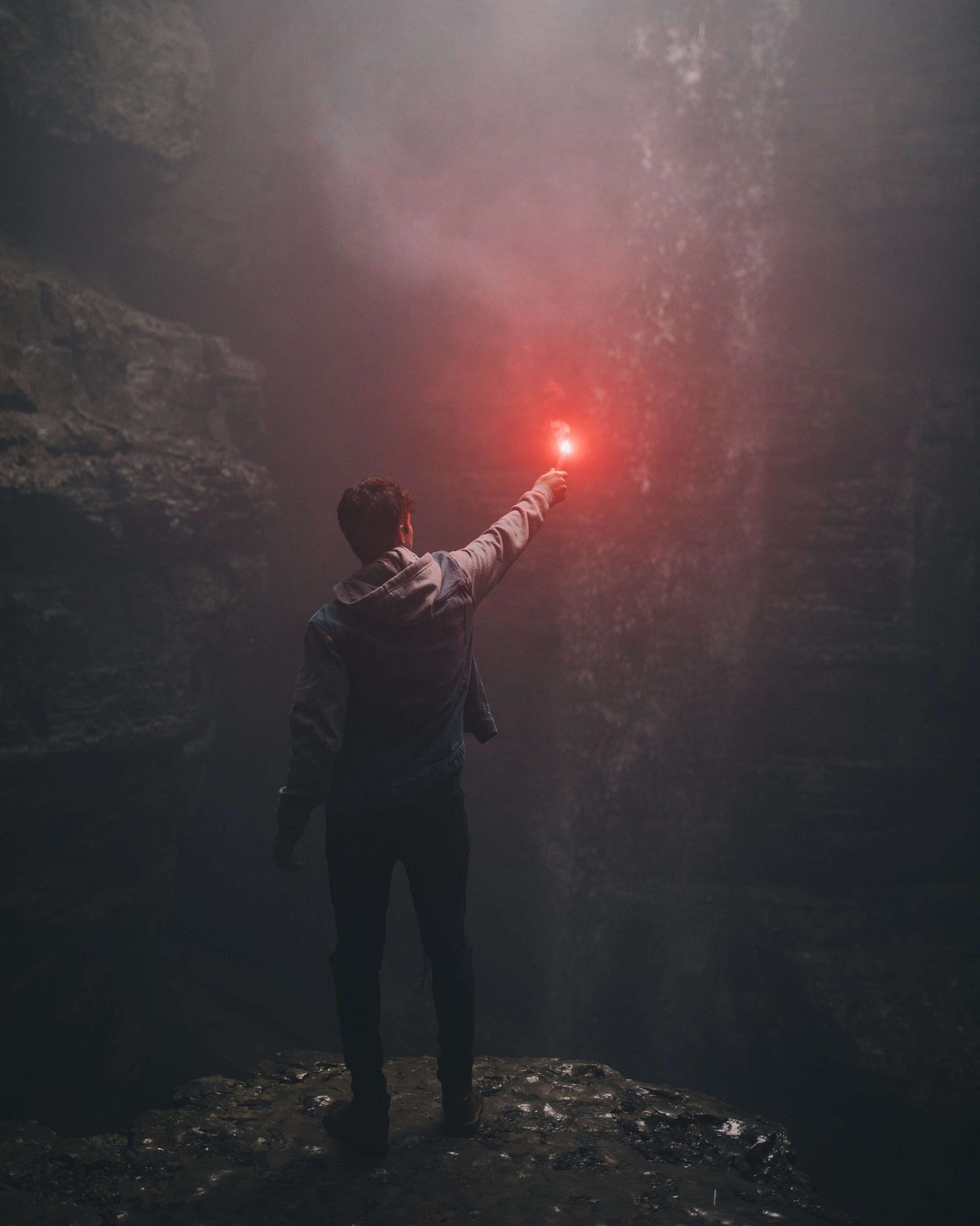 Guy holding red torch in darkness to shine a light.