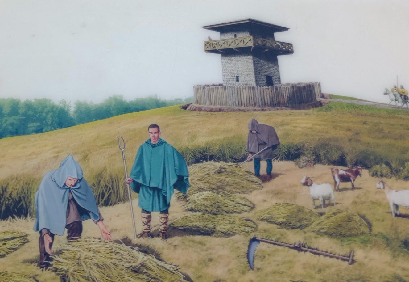 Farmers harvesting hay, while someone enjoys the view from the Roman tower in the background, the only remnant of Hadrian's Wall in the background