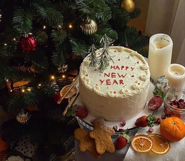 This may contain: a decorated cake on a table next to a christmas tree with oranges and other decorations