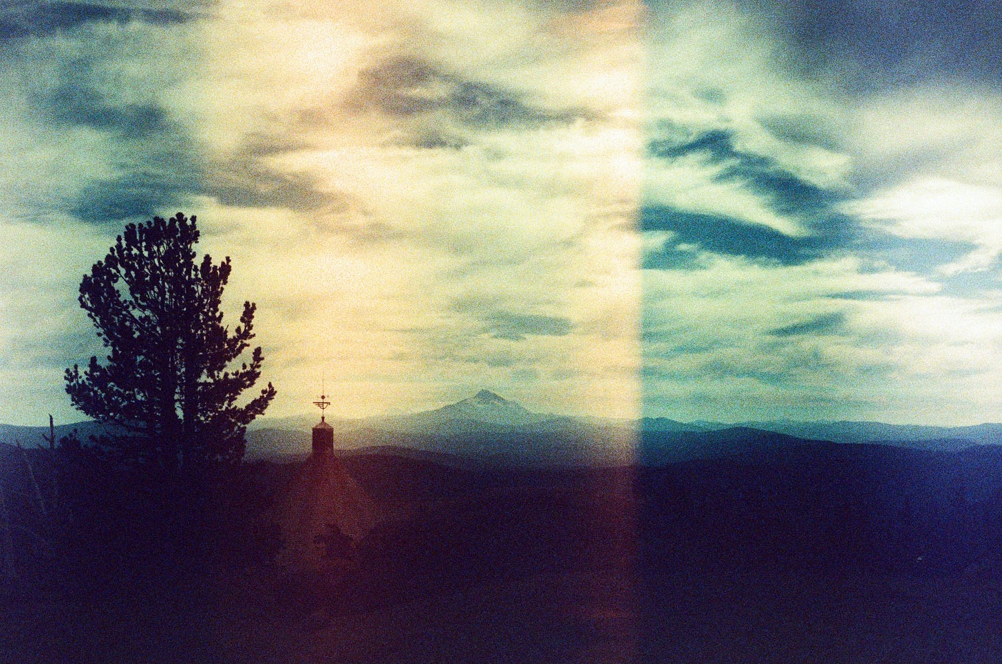 A dark film photo with a bright sky, and an almost-black tree off to the left.