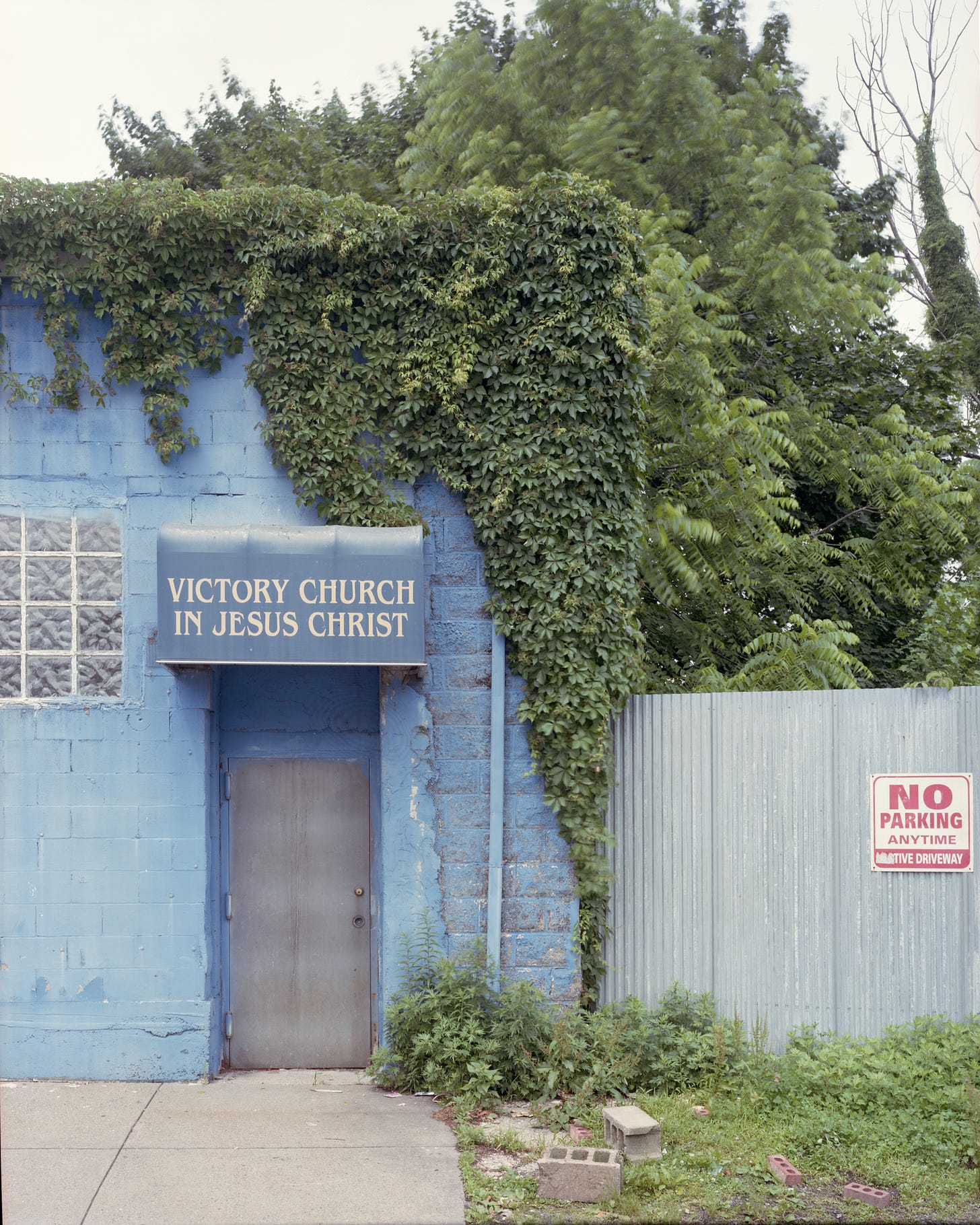 Victory Church in Jesus Christ, blue wall and awning covered in ivy
