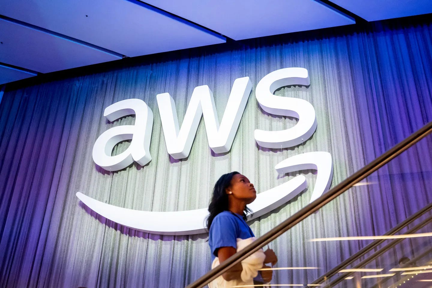 A woman walking up a stairwell in front of an AWS sign