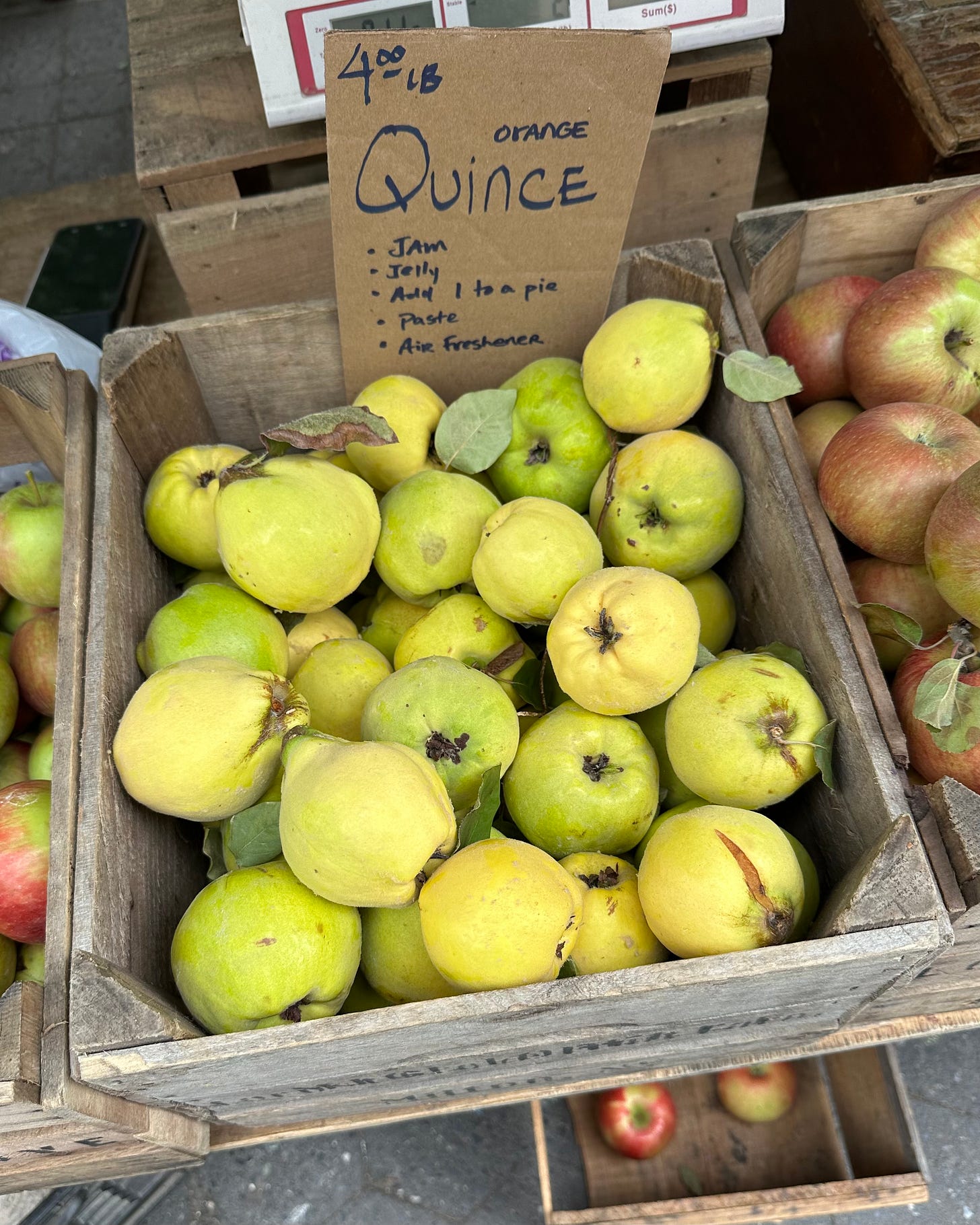 A wooden box filled with quince fruit at a farmers' market.