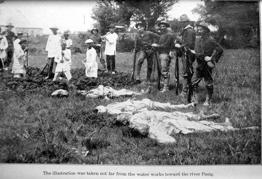 Des soldats américains posent devant les cadavres de prisonniers philippins qu'ils viennent d'exécuter