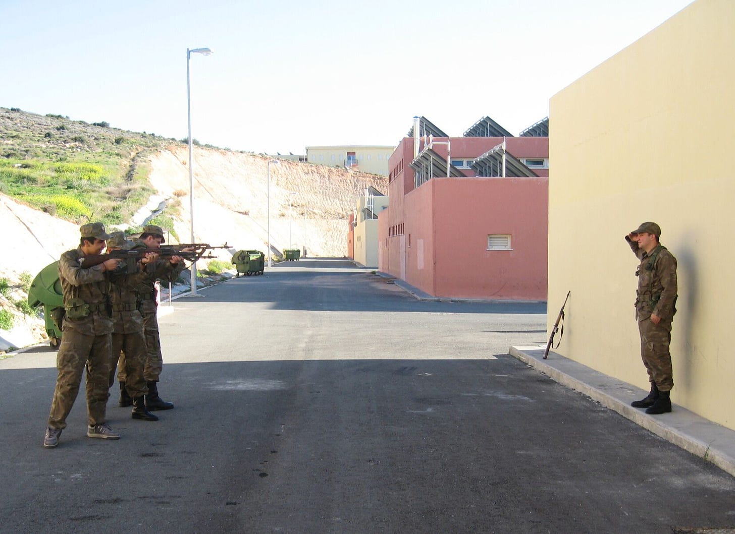 a row of conscripts pointing guns at another conscript who is against a wall in a mock execution