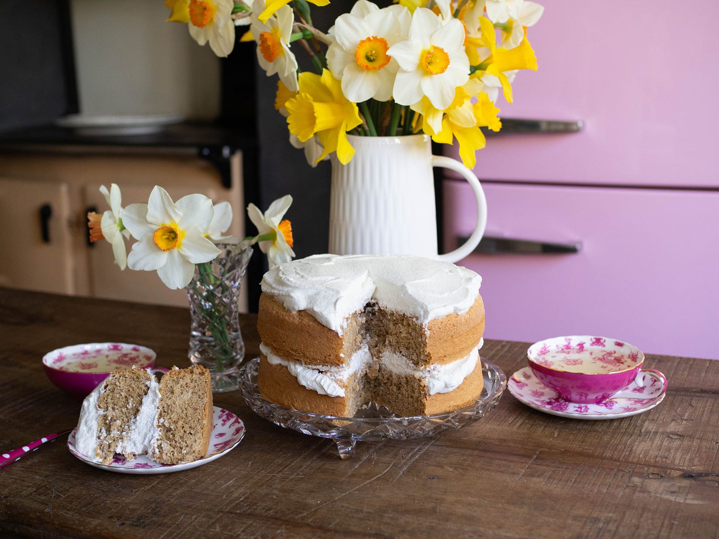 double layer ginger sponge cake with cream vase of daffodils behind cake