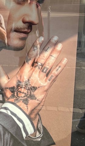 A close up of a hand with tattoos

Description automatically generated with low confidence