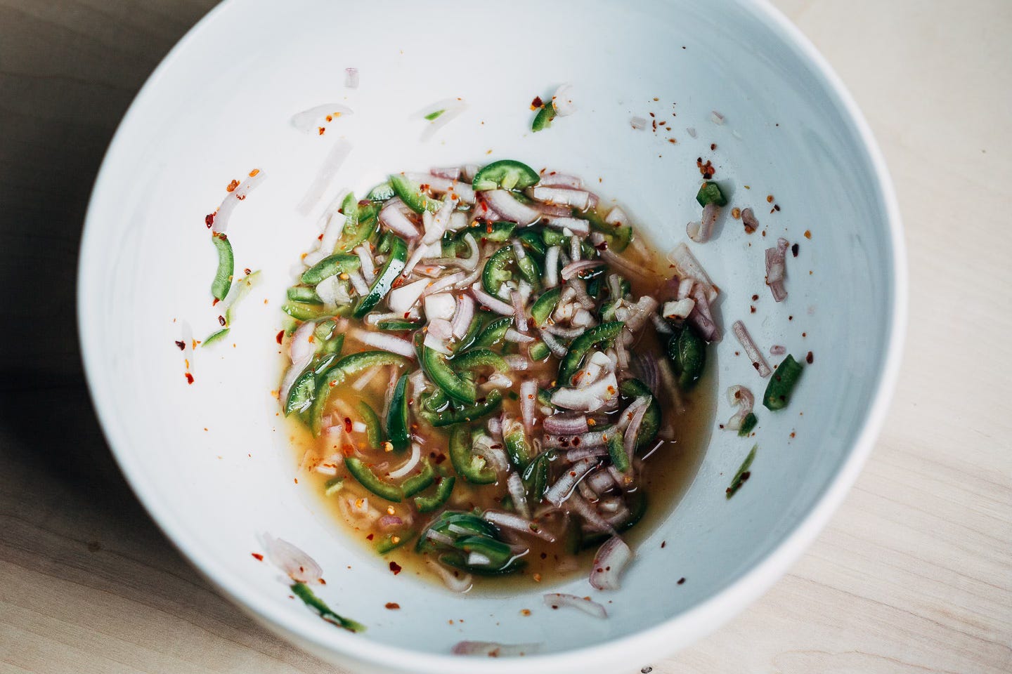 A white bowl with shallots and jalapenos