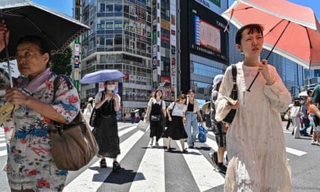 People using umbrellas and parasols to seek relief from the heat while crossing a street in Tokyo, as temperatures of 35C-plus have scorched the Japanese capital for weeks