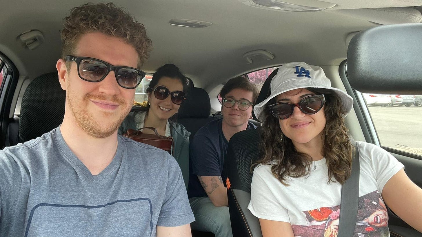 Four people smile at the camera sitting inside a car