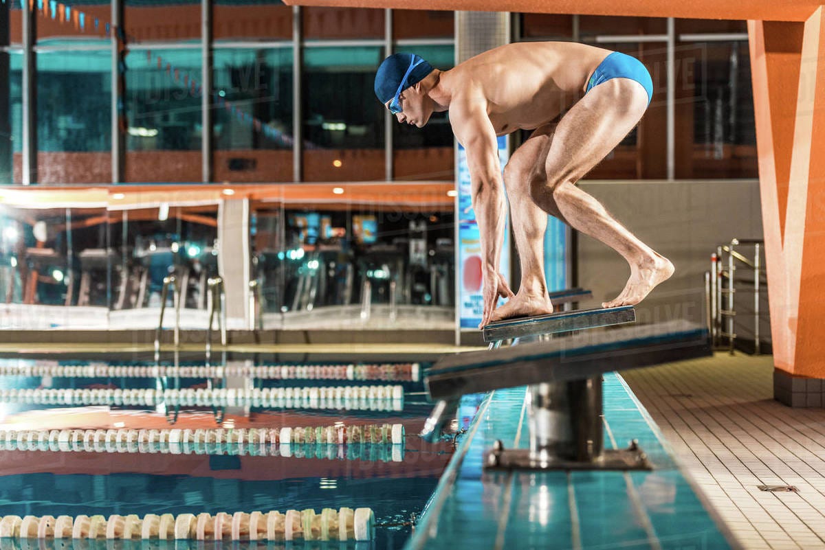 Swimmer standing on diving board ready to jump into competition swimming  pool - Stock Photo - Dissolve