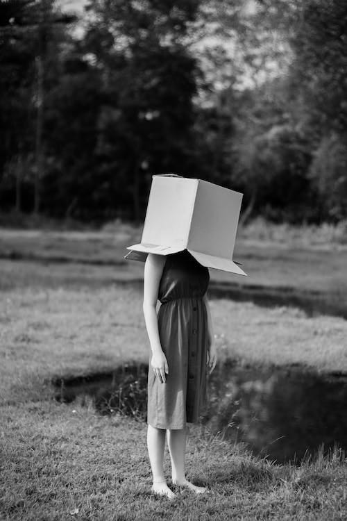 Free Faceless woman with cardboard box on head against pond Stock Photo