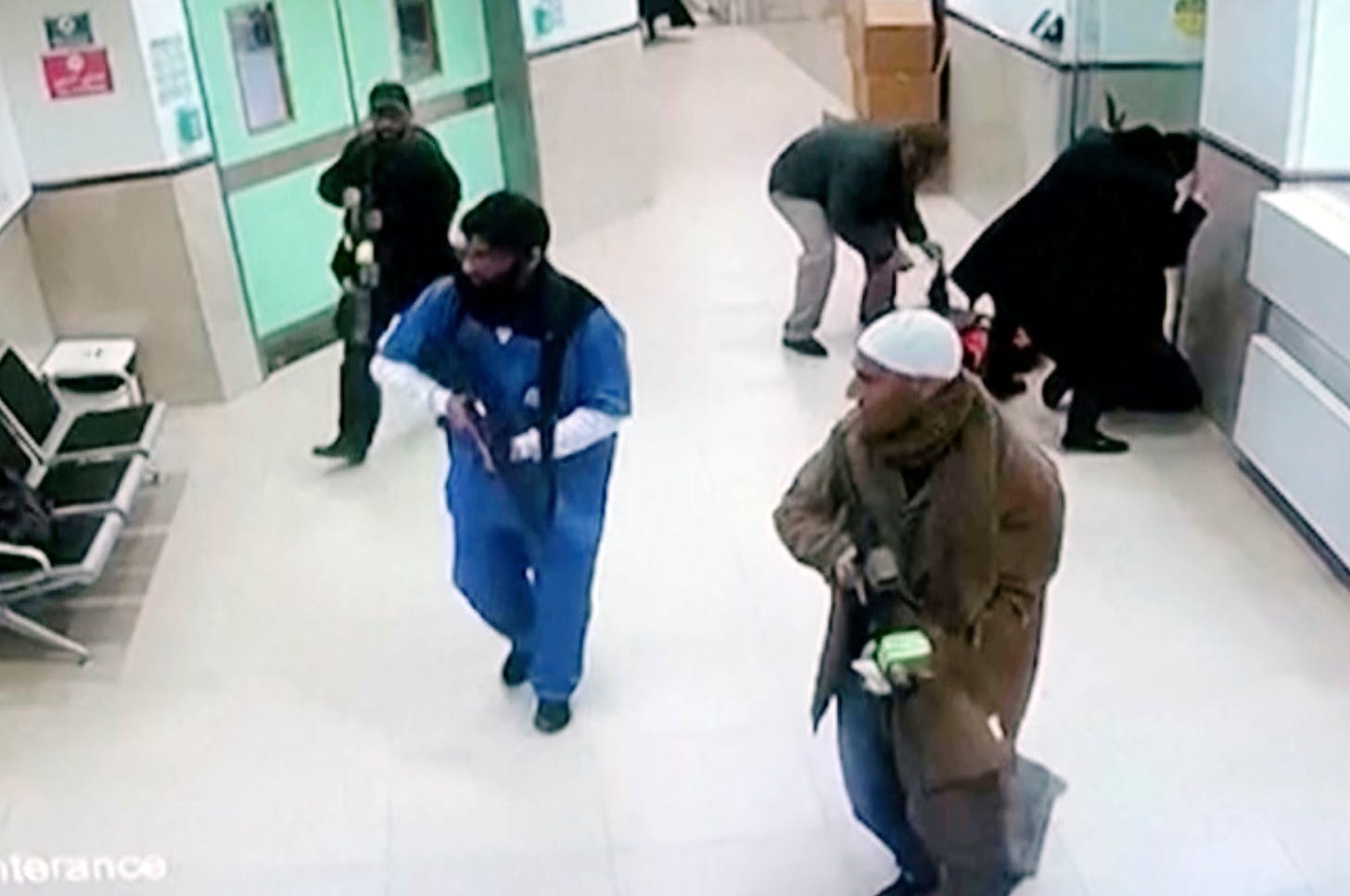 Still from surveillance video showing three armed men dressed as civilians and a hospital worker in a hospital hallway.