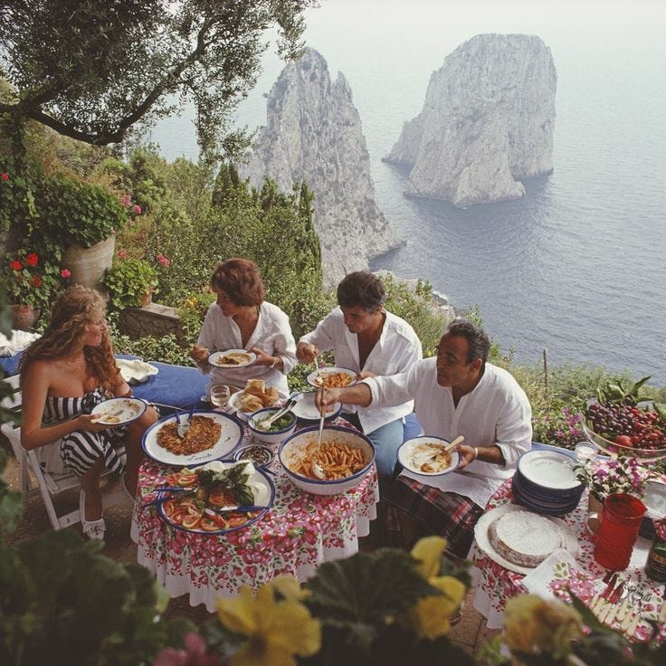 This may contain: a group of people sitting around a table with plates of food in front of them