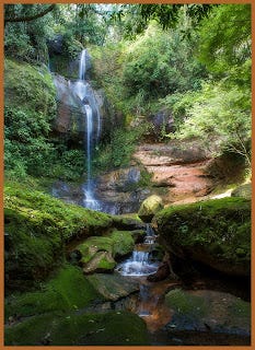 cachoeira grande com uma corredeira e algumas gramas e vegetações em volta