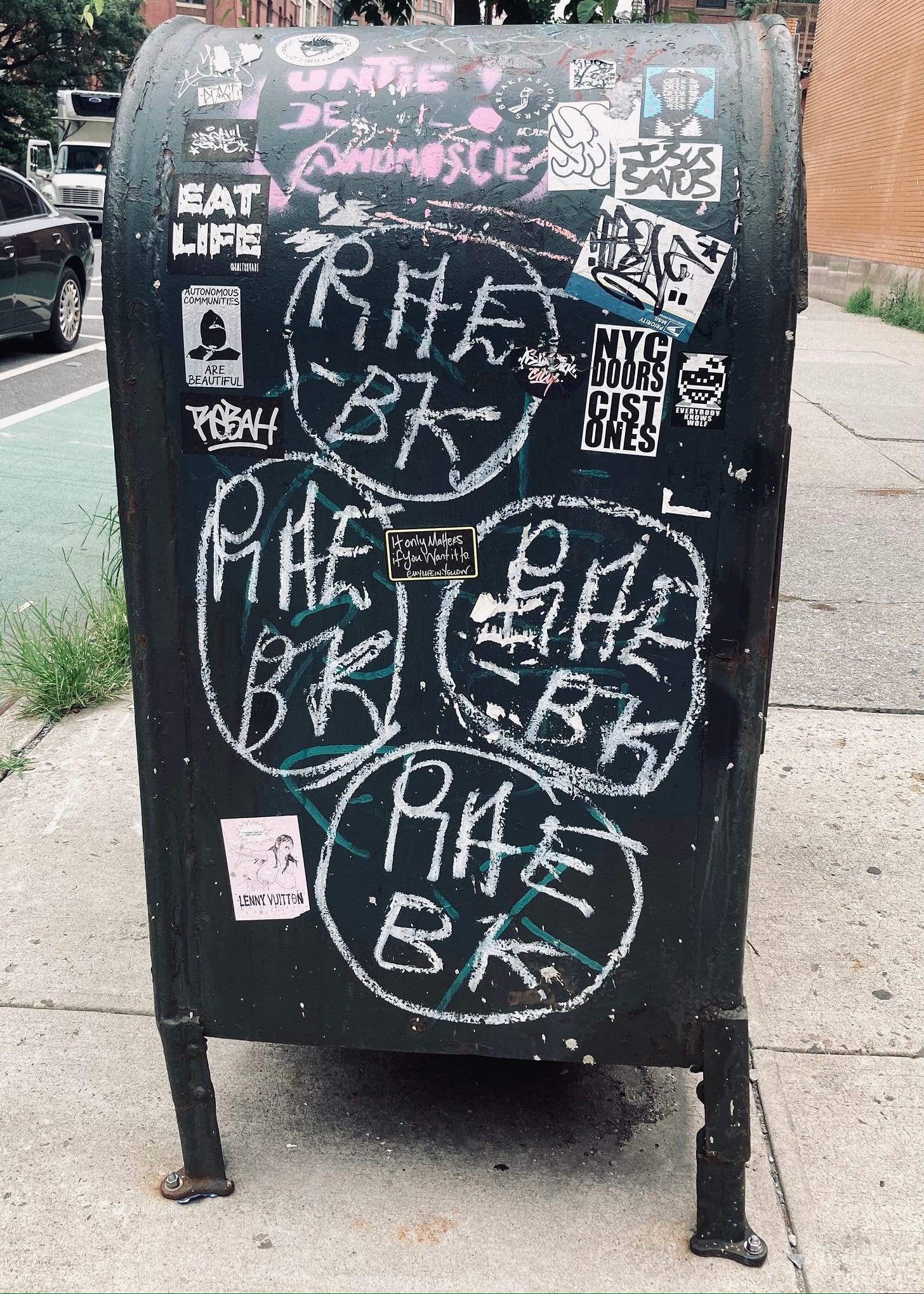 sidewalk mailbox covered with graffiti and stickers, including stickers that say Eat Life and It only matters if you want it to
