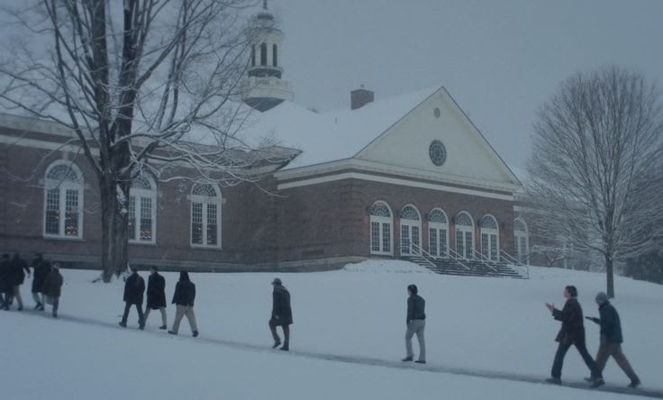 This may contain: several people walking in the snow near a building