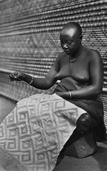 A Kuba woman sewing an applique on raffia cloth; early to mid 20th century from the Tropenmuseum