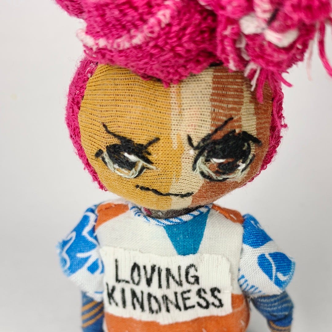 An angry artist girl doll that wears a Loving kindness tee