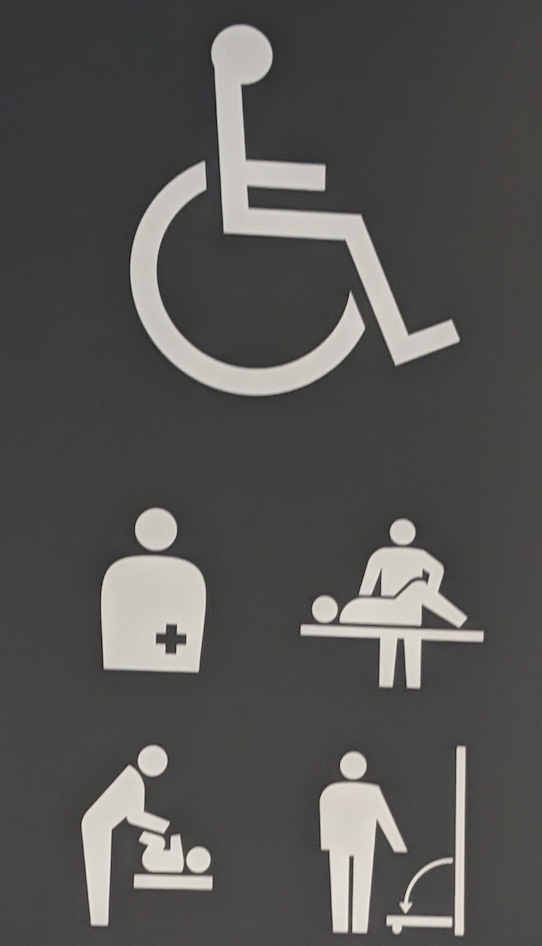 Handicapped sign that includes anyone with a small child, outside a restroom