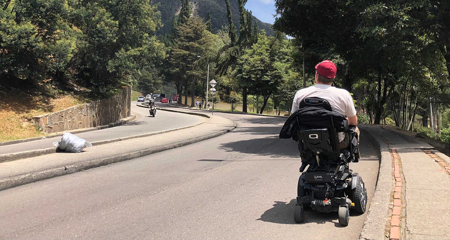 Wheelchair rolling along street next to sidewalk in Bogota, Colombia.