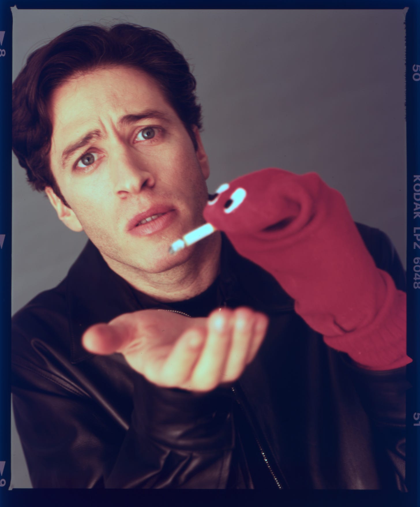 Jon Stewart using a sock puppet to smoke a cigarette.