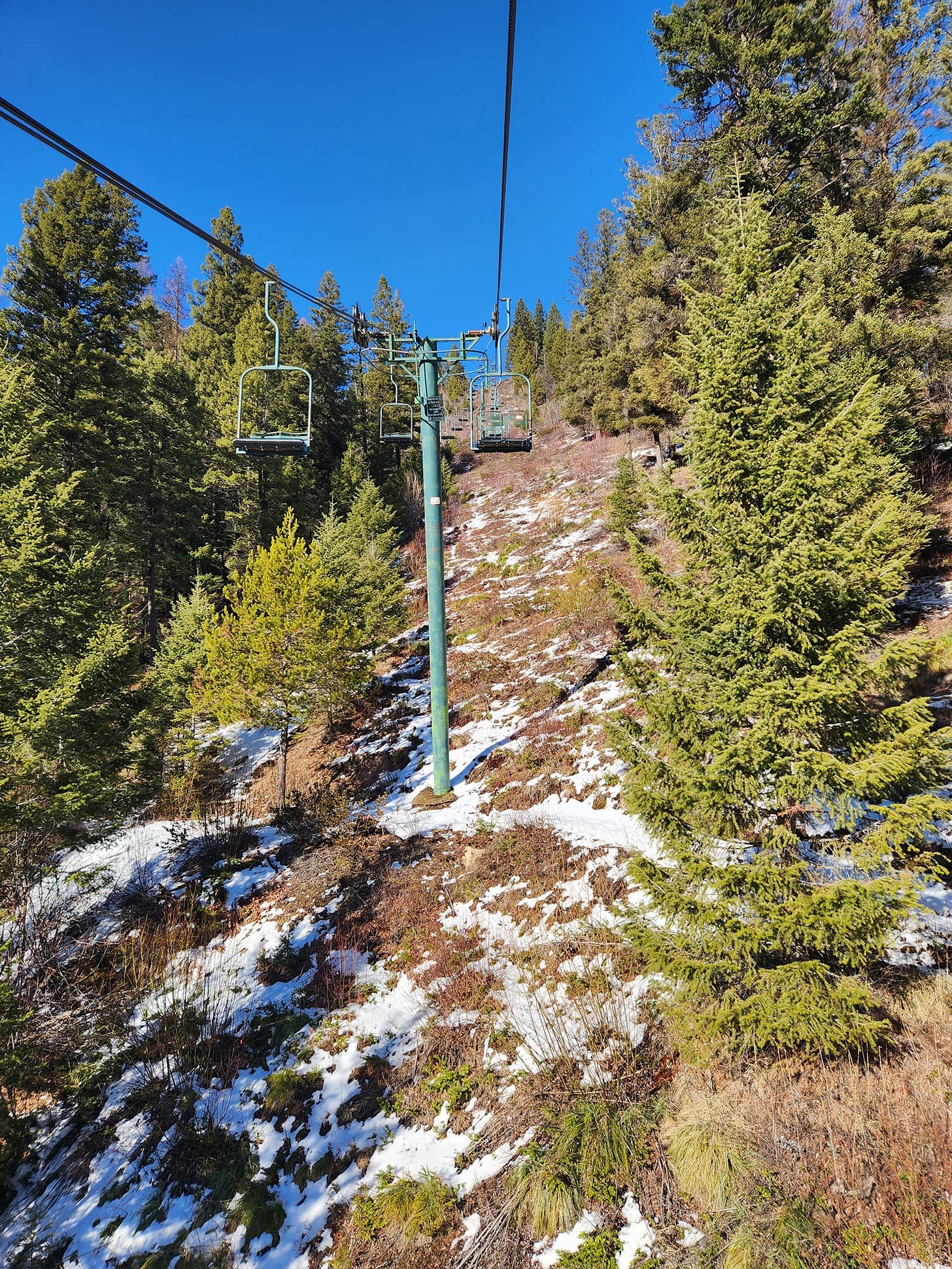 bluebird day on ski lift but no snow just rocks underneath