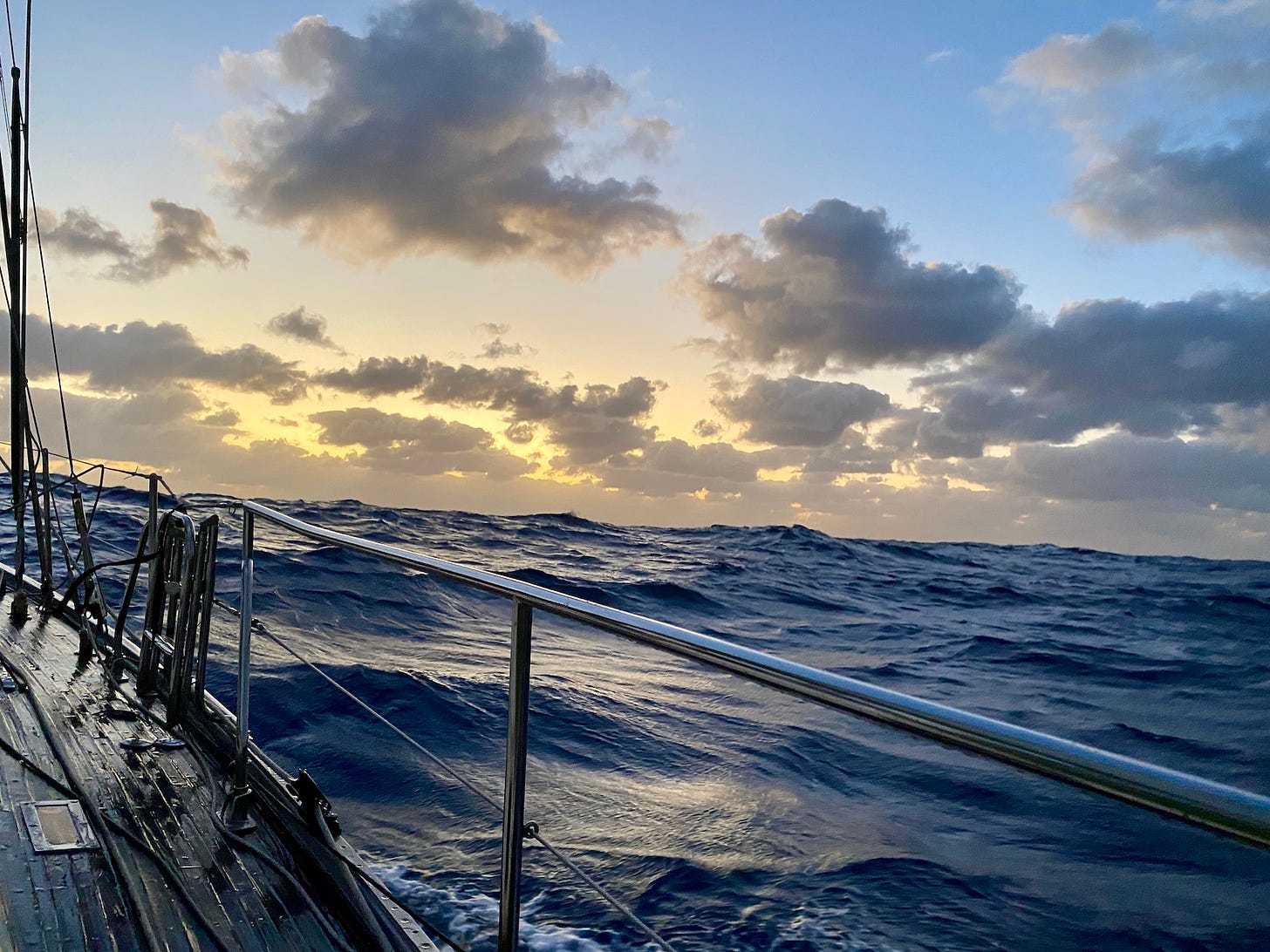 Sunrise on the ocean. The sea state is vigorous with lots of waves and the sunrise is a soft yellow.