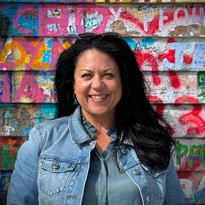 Rebecca Blackwell standing in front of a graffiti covered wall.