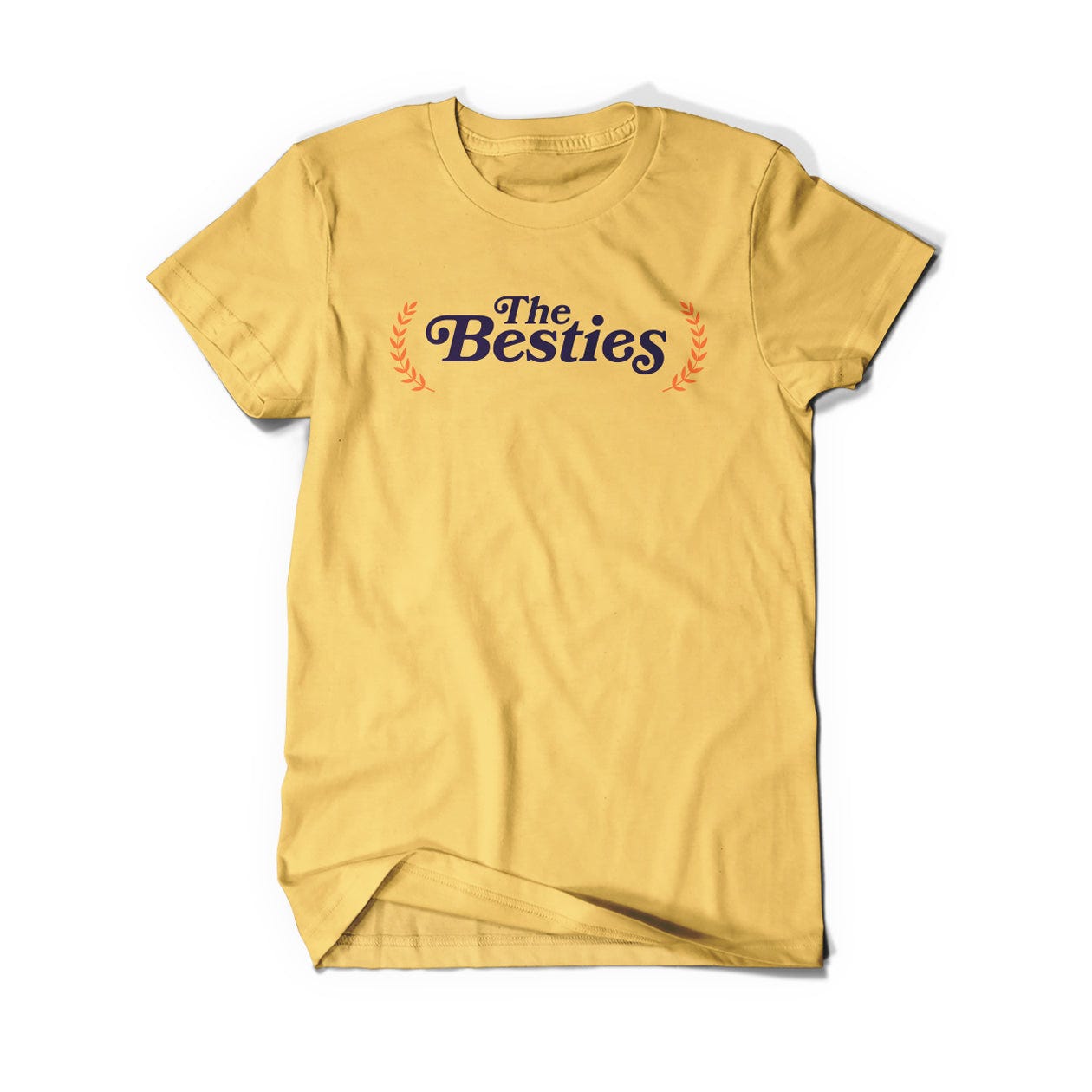 A gold shirt that says, "The Besties" in black serif font with an orange laurel on either side.