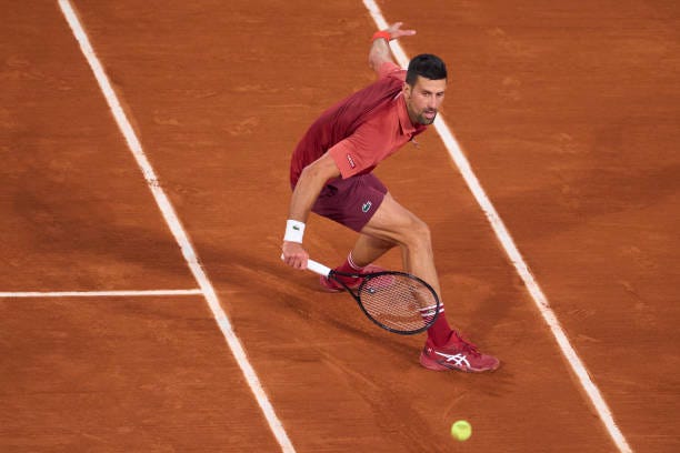 Novak Djokovic of Serbia plays a backhand against Lorenzo Musetti of Italy in the Men's Singles third round match on Day Seven of the 2024 French...