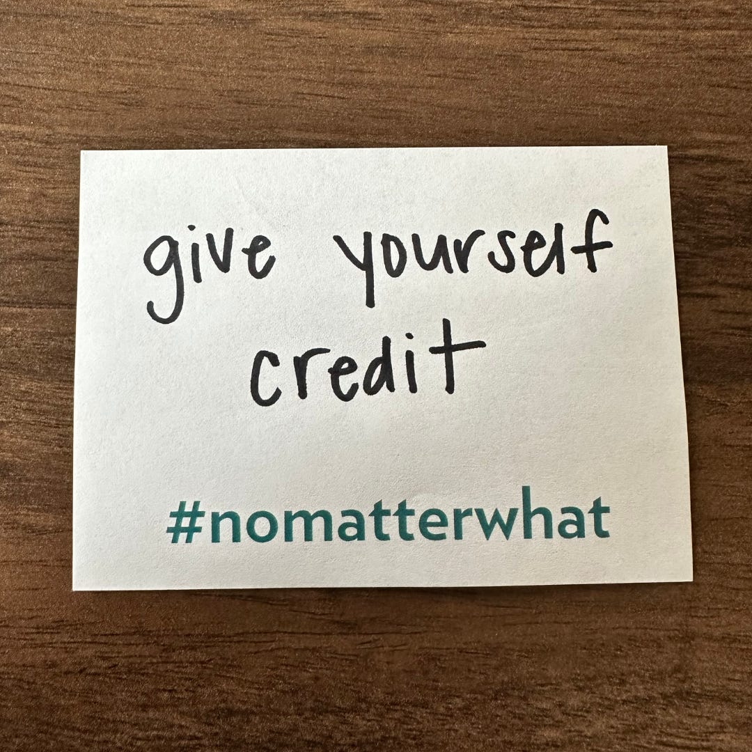 a photo of a sticky note that has, “give yourself credit” written on it and includes #nomatterwhat preprinted on the bottom