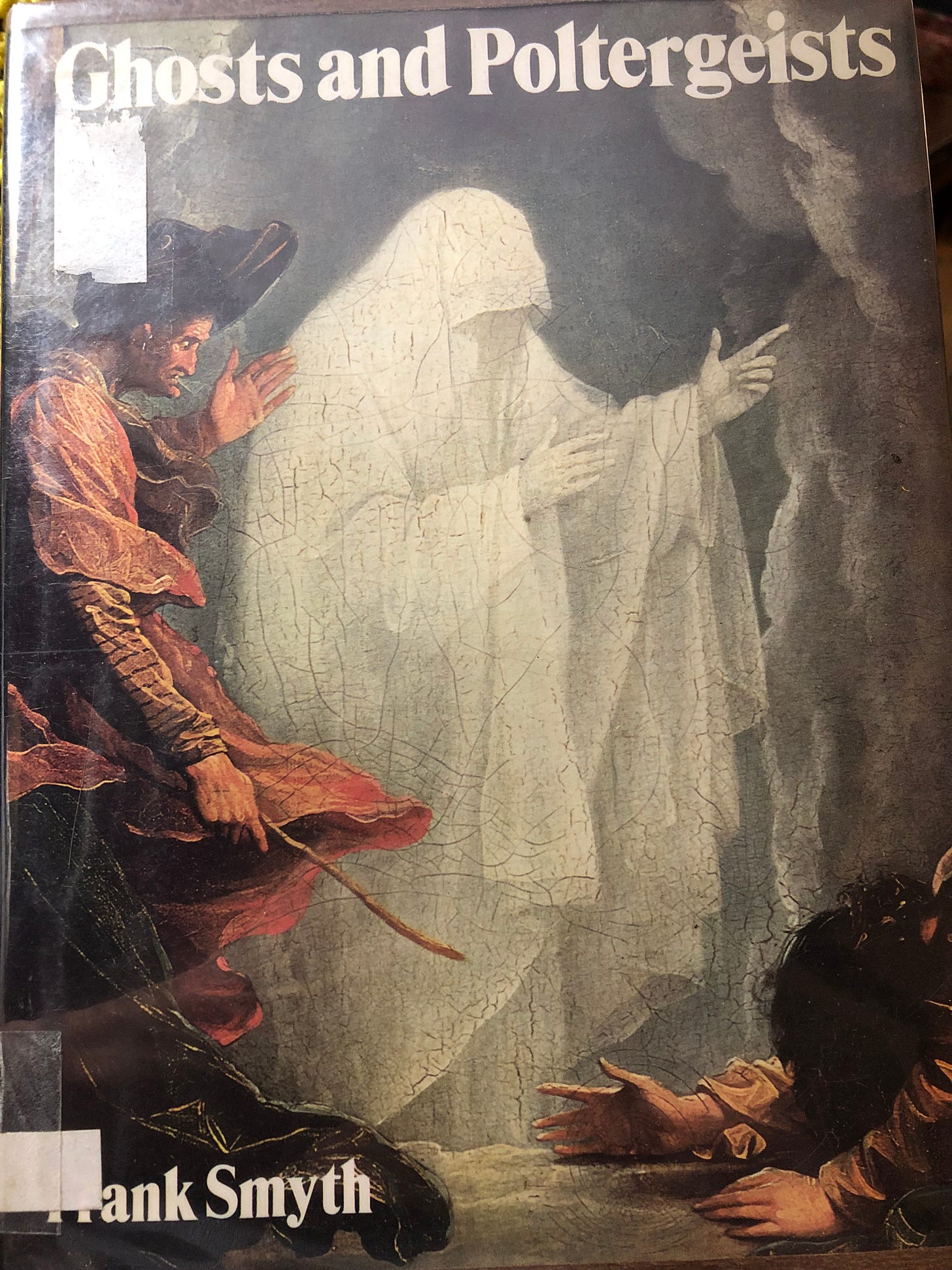 A ghost in a white sheath stands over a prostrate man while another man points a stick at him. 