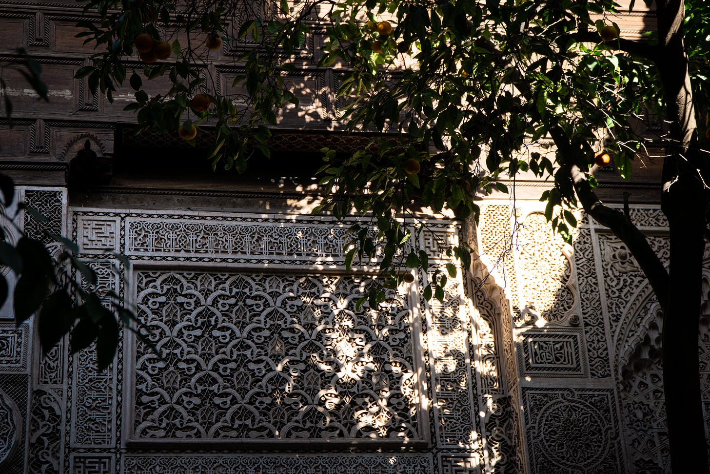 Shadows and sun playing on a courtyard wall carved in Islamic designs 
