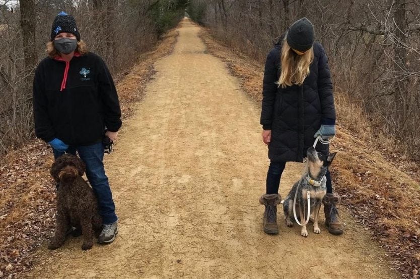 Scout the Australian cattle dog posing next to her owner, her owner's mom, and her owner's family dog on the Mountain Bay Bike Trail