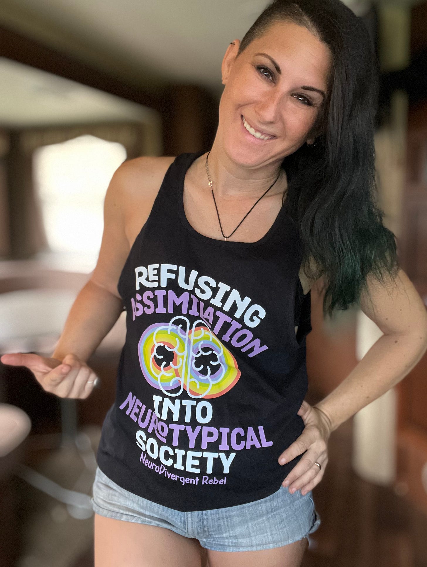 Lyric posing in a black tank top that says refusing assimilation into Neurotypical society