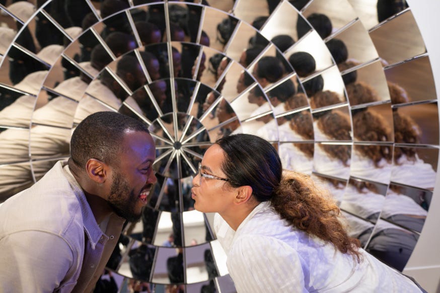 Two people facing off against each other in front of a large mirrored object