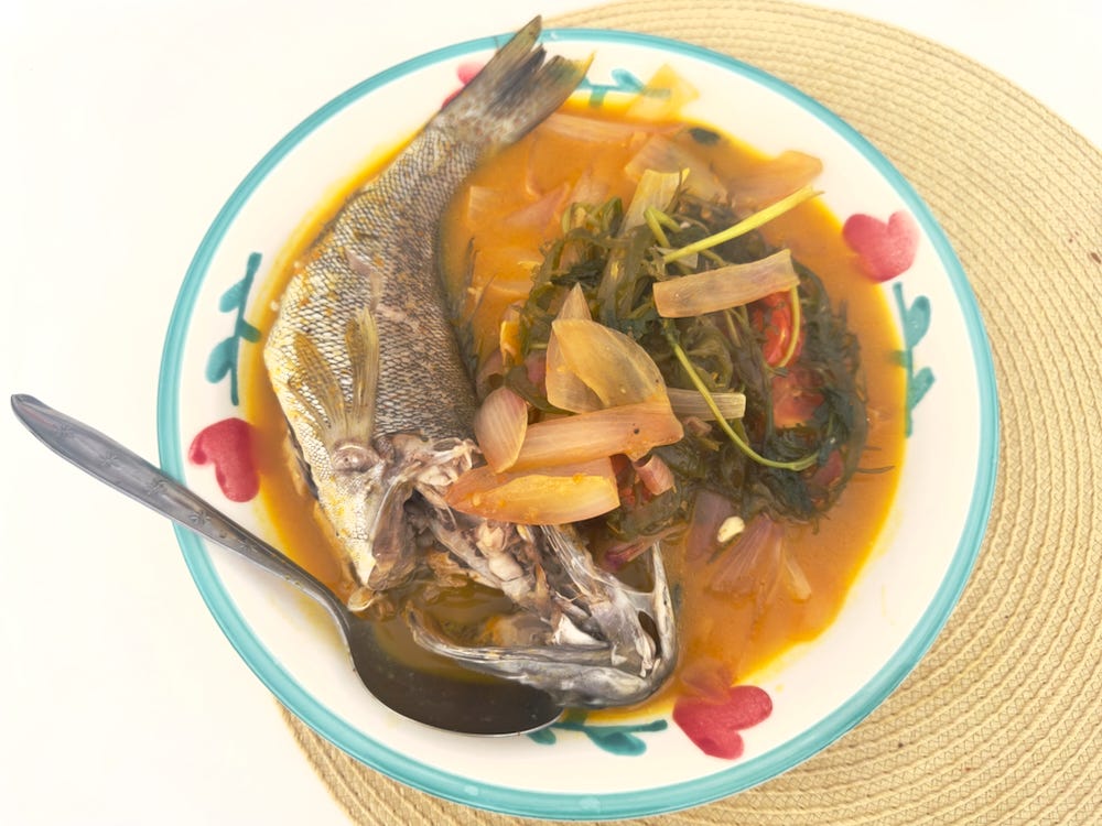Whole fish in a yellow pepper sauce with onions and tomatoes and seaweed