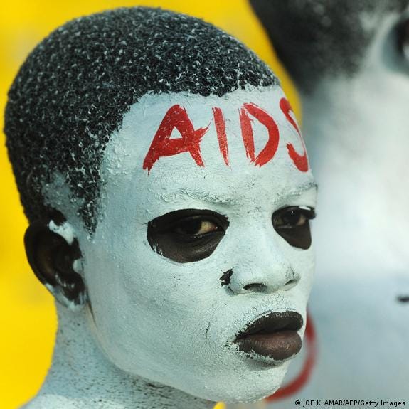 A boy has his face painted white with the word AIDS in red on his forehead