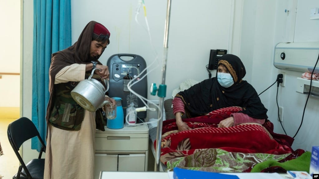 FILE - An Afghan man prepares tea for a relative being treated for COVID-19 in the Afghan-Japan Hospital in Kabul on Dec. 9, 2021. Afghanistan's health care system is on the brink of collapse and able to function only with a lifeline from international aid organizations.