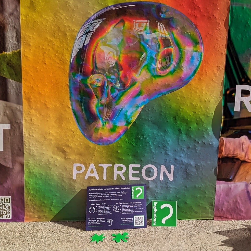 A big multicoloured gradient Patreon logo on a textured wall along with small Lingthusiasm logo stickers and bouba/kiki stickers on the ledge in front