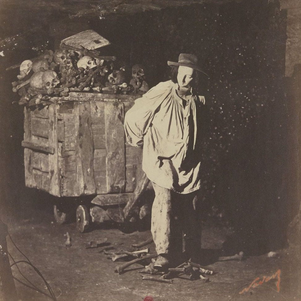 Historic photograph of catacombs exhibit showing mannequiin pulling cart loaded with human bones