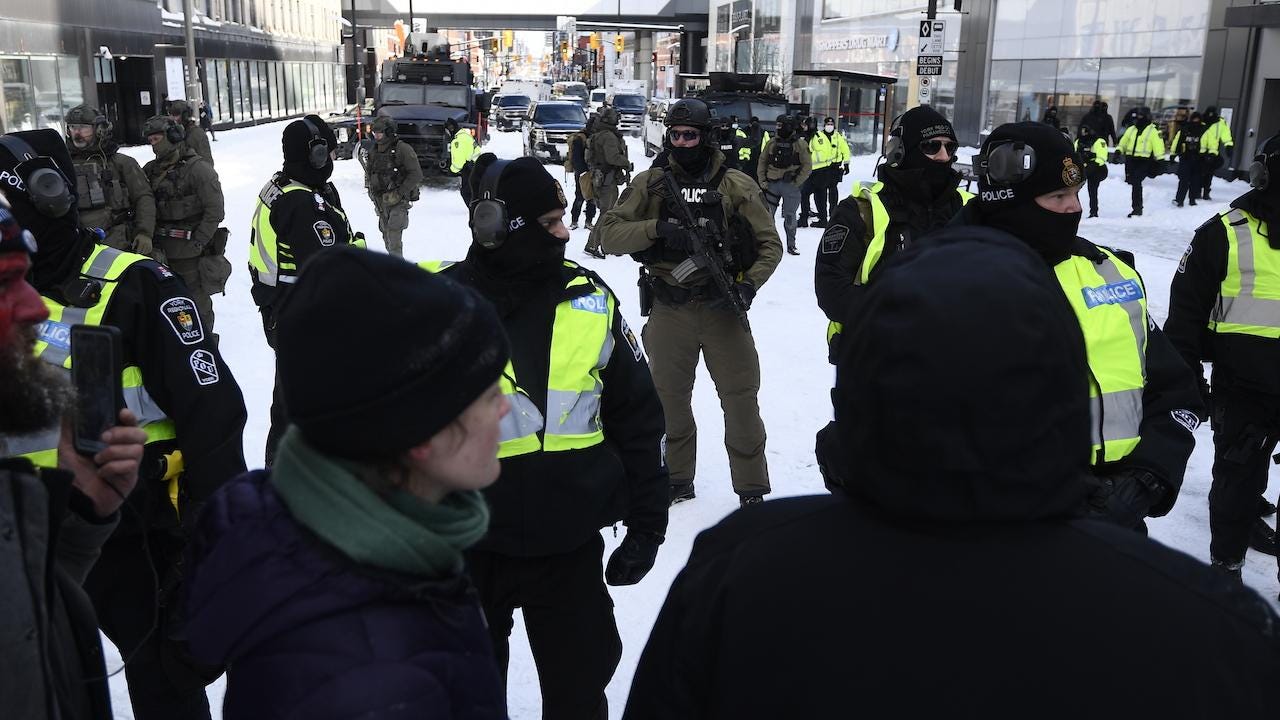 police in tactical gear stand on a snowy city street