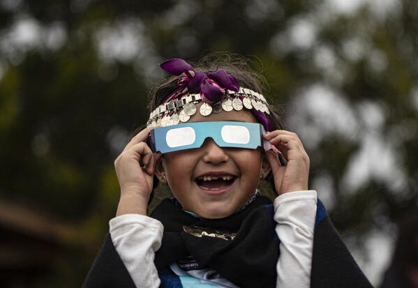 FILE - Magdalena Nahuelpan, a Mapuche Indigenous girl, looks at a total solar eclipse using special glasses in Carahue, La Araucania, Chile, Monday, Dec. 14, 2020. The total eclipse was visible from Chile and the northern Patagonia region of Argentina, and as a partial solar eclipse in Bolivia, Brazil, Ecuador, Paraguay, Peru and Uruguay. (AP Photo/Esteban Felix, File)