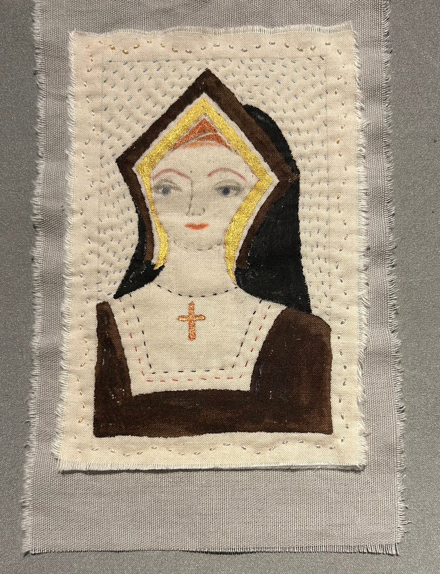 A stitched portrait of Katherine of Aragon, on a grey background. She wears dark colours and a gable hood, and a crucifix around her neck. 